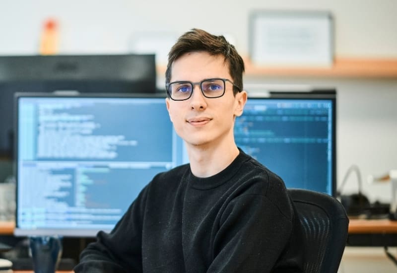 Centic softwareudvikler i sort trøje foran computer
